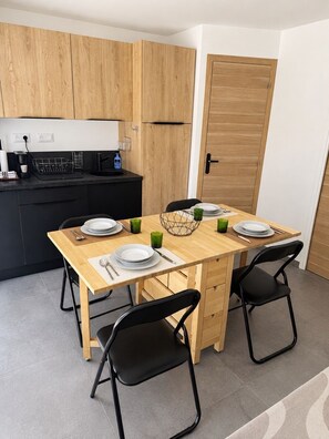 Eine kompakte Küche mit Holzschränken, einer schwarzen Arbeitsplatte und einem Essbereich mit einem Holztisch und schwarzen Stühlen.