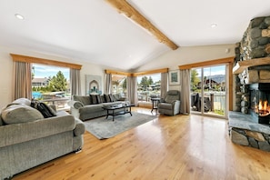 A spacious living room with a fireplace, wooden flooring, and large windows. - Pet Friendly Waterfront Retreat with Private Boat Dock (South Lake Tahoe)