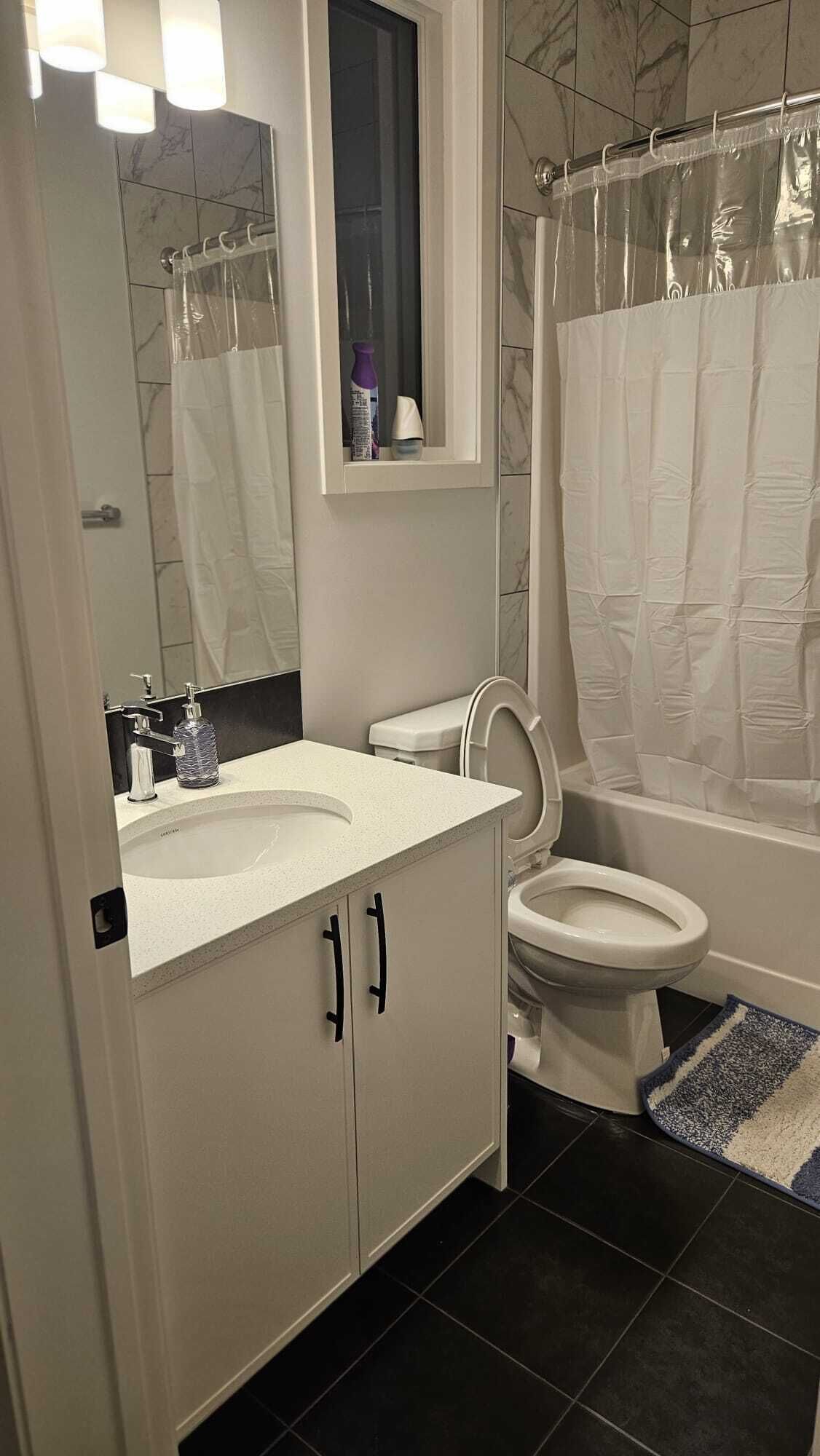Een badkamer met een witte wastafel, toilet en douchegordijn.
