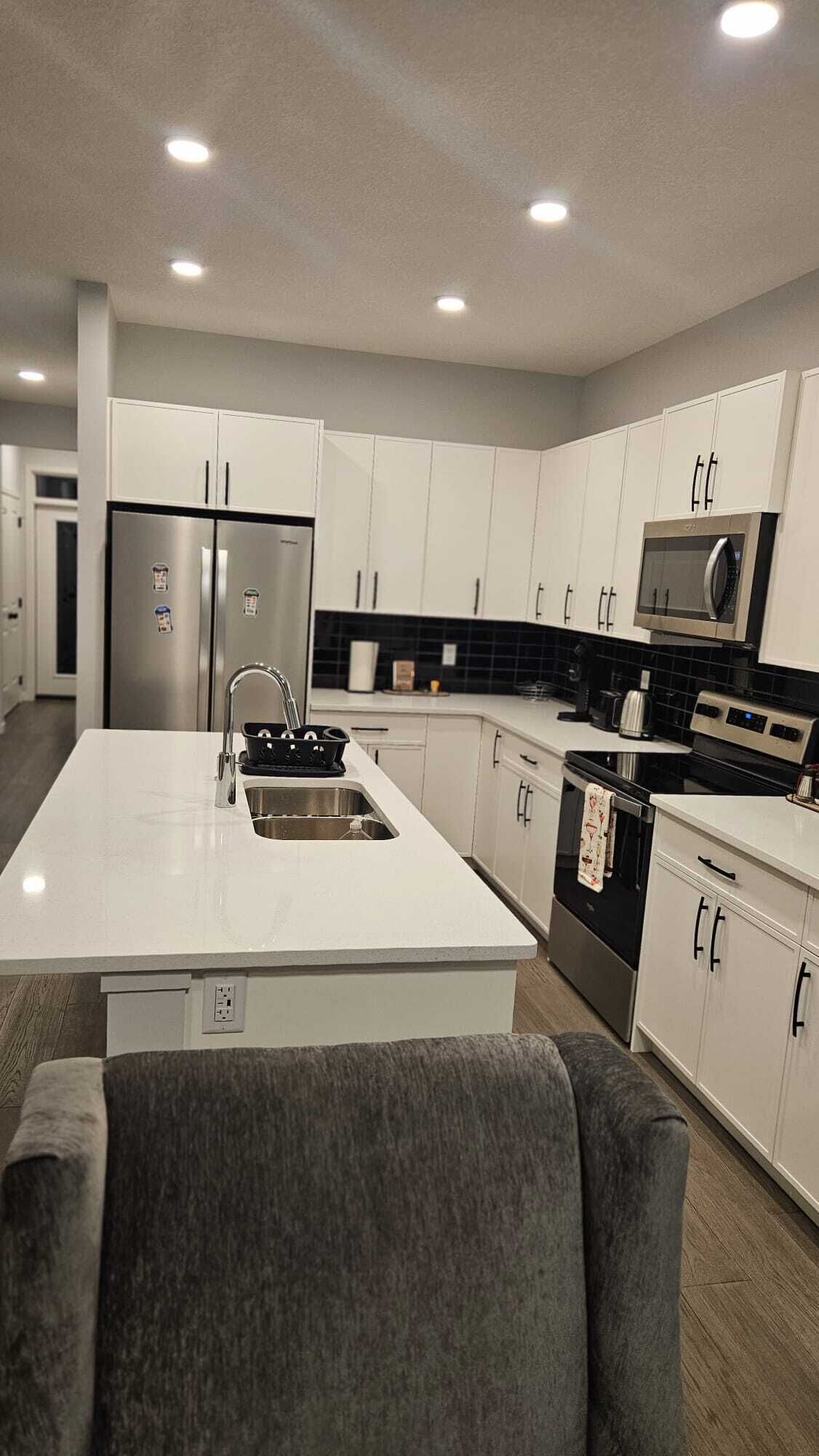 Una cocina moderna con armarios blancos, electrodomésticos de acero inoxidable y una isla central.