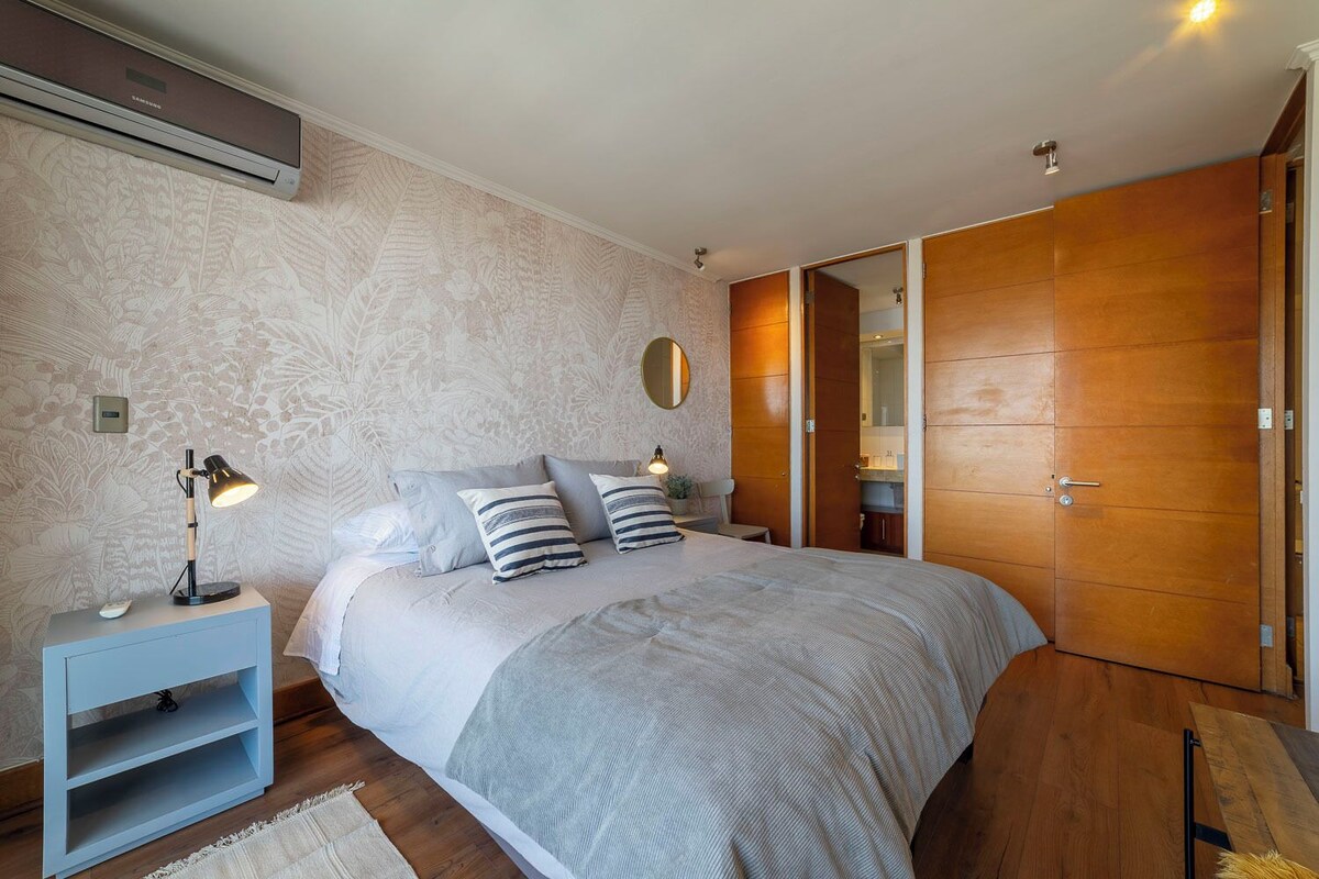 A bedroom with a bed, bedside tables, a wardrobe, and a wall-mounted air conditioner.