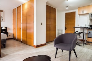 Ein Hotelzimmer mit einem Bett, einem Sessel, einem Schreibtisch mit Computer und einer Küchenzeile.
