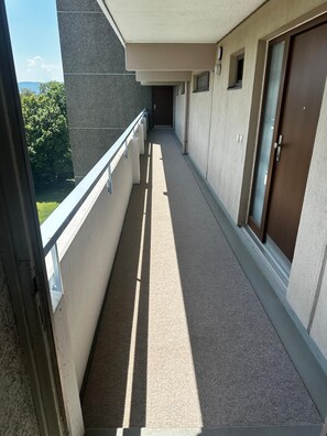 Ein schmaler Korridor mit einem Balkon an der Seite, der zu einer Tür führt.