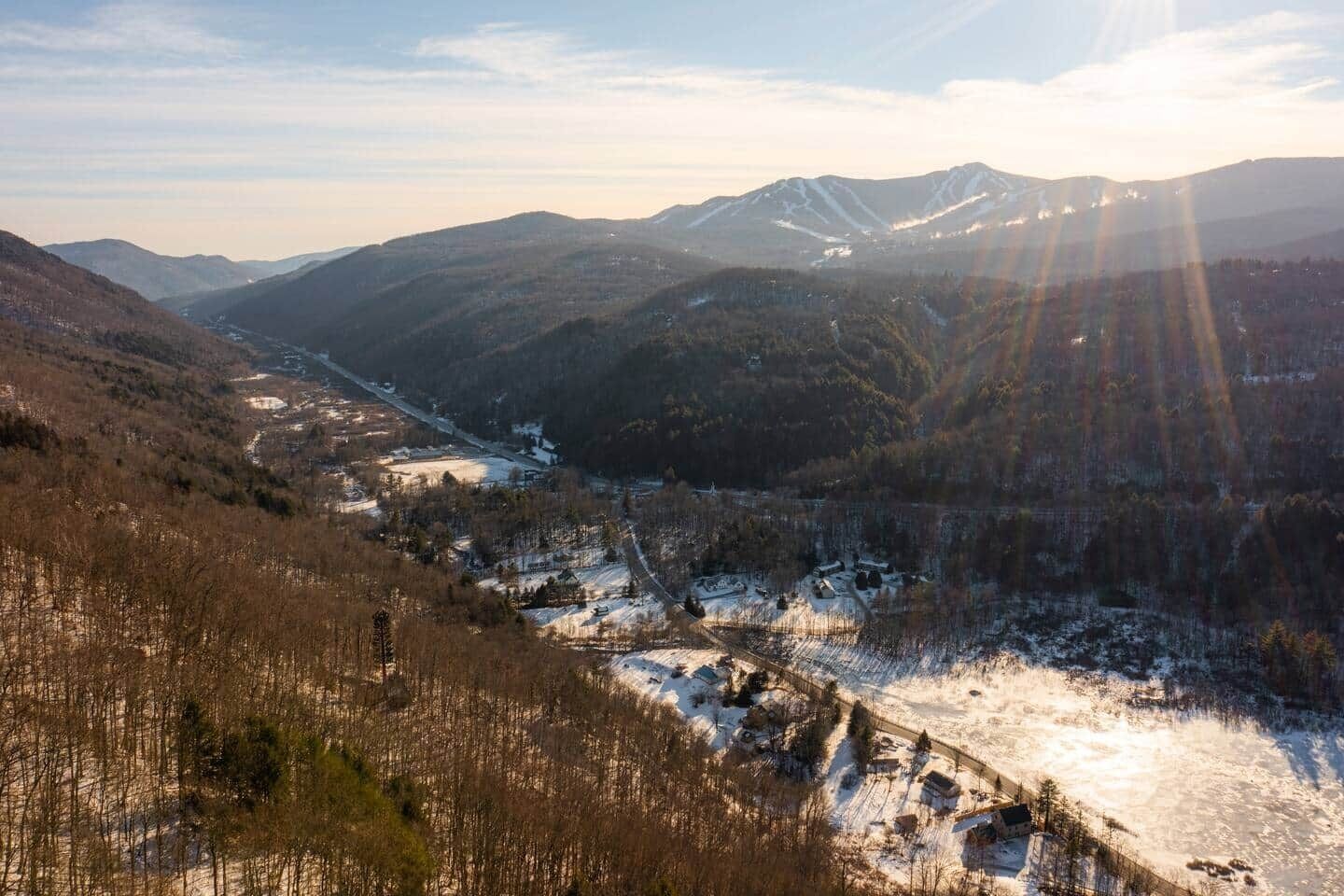 A mountainous landscape with a valley, snow-covered ground, and a clear sky.