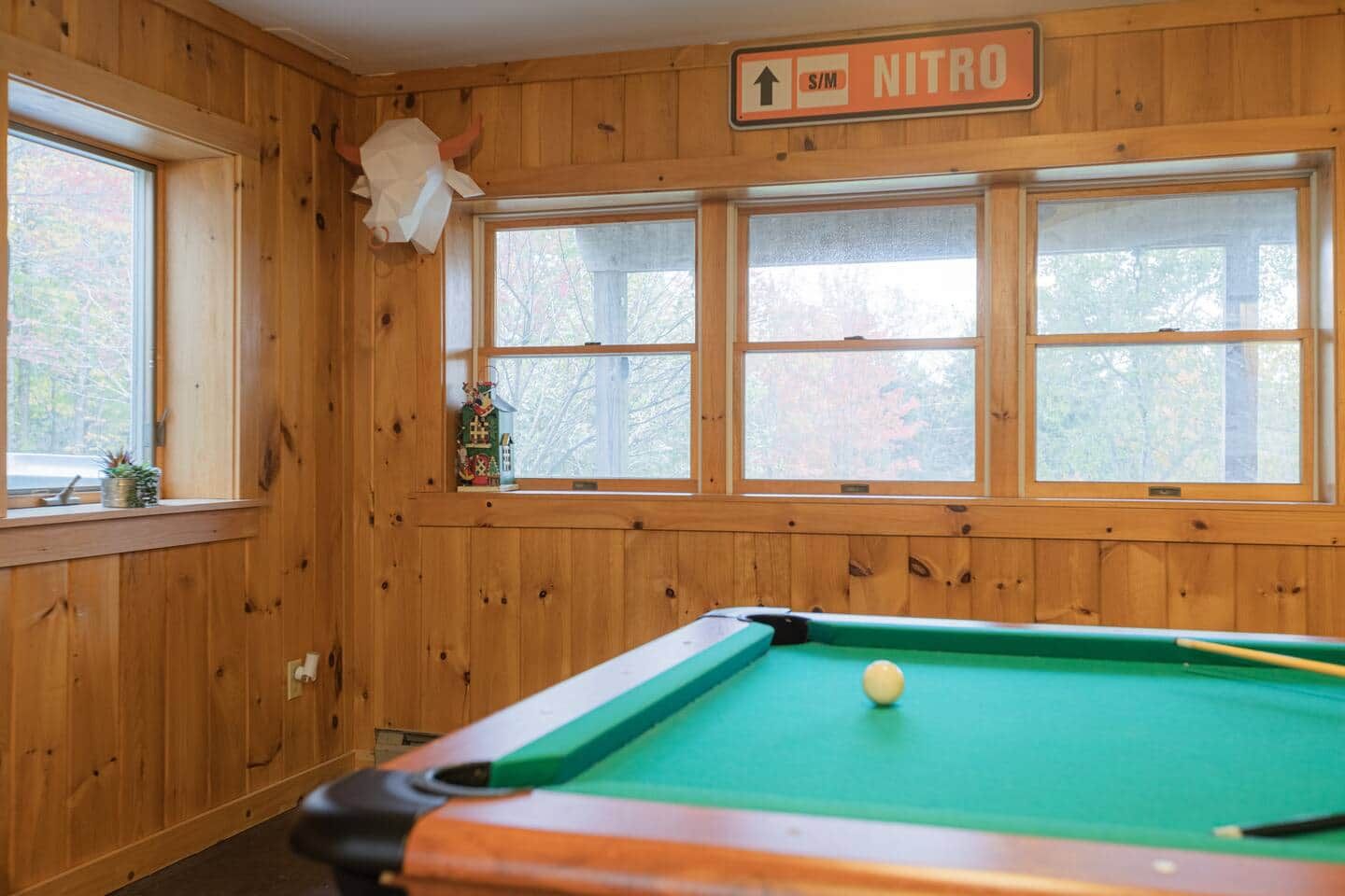 Een pooltafel in een ruimte met houten wanden en ramen.