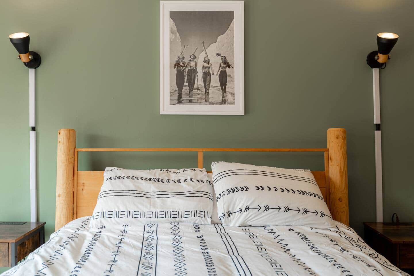 Ein Schlafzimmer mit einem hölzernen Kopfteil, einem Bett mit gemusterten Betttextilien und einem gerahmten Bild an der Wand.