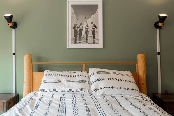 A bedroom with a wooden headboard, a bed with patterned bedding, and a framed picture on the wall.