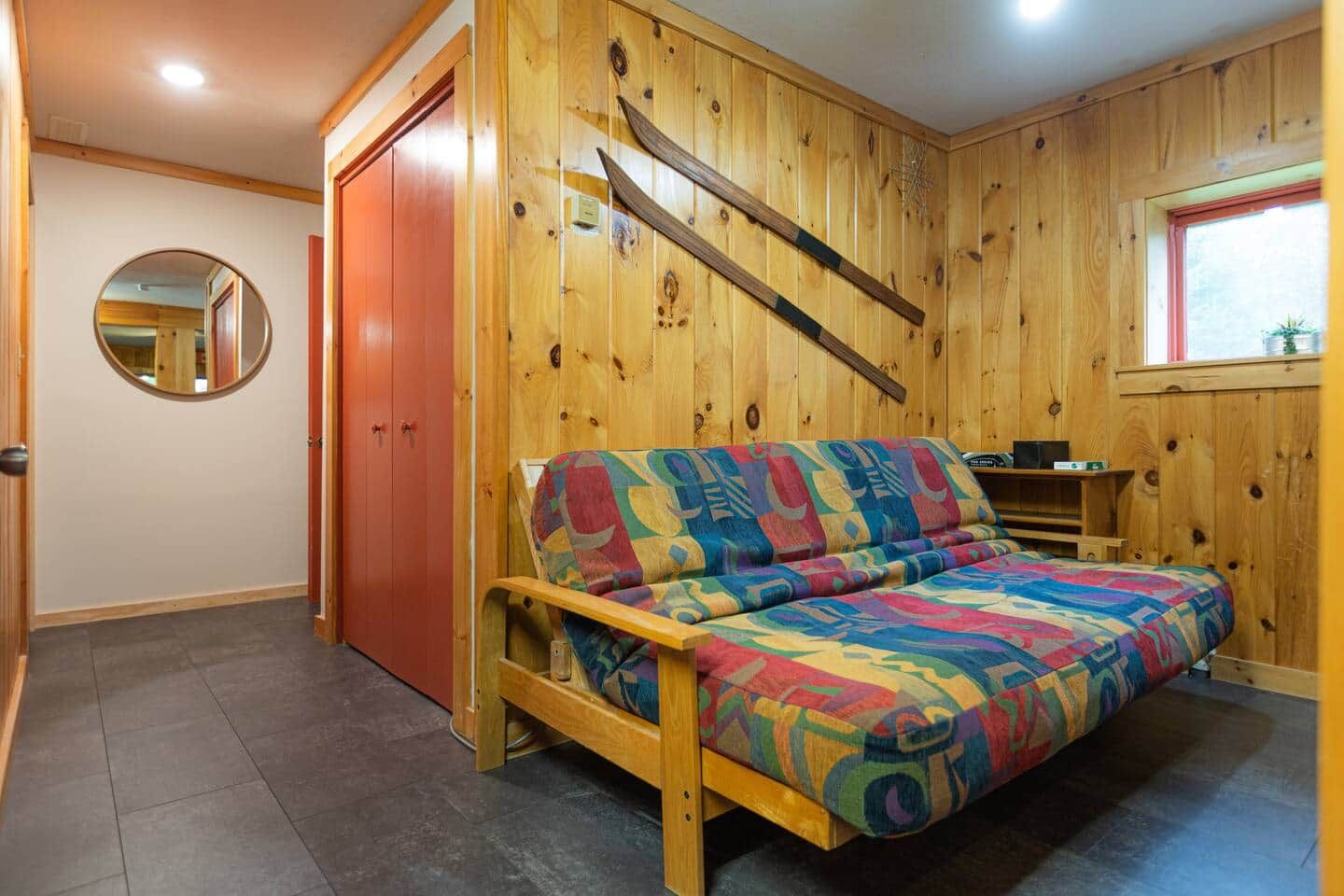 Een kamer met een houten bed, een spiegel en een raam.