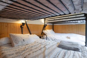 A bunk bed room with wooden paneling and a headboard. There are two beds, one with a patterned bedspread and pillows, and another with a plain bedspread. - MtSnow* HotTub*  Pool * AirHockey*PingPong * Darts (Wilmington)