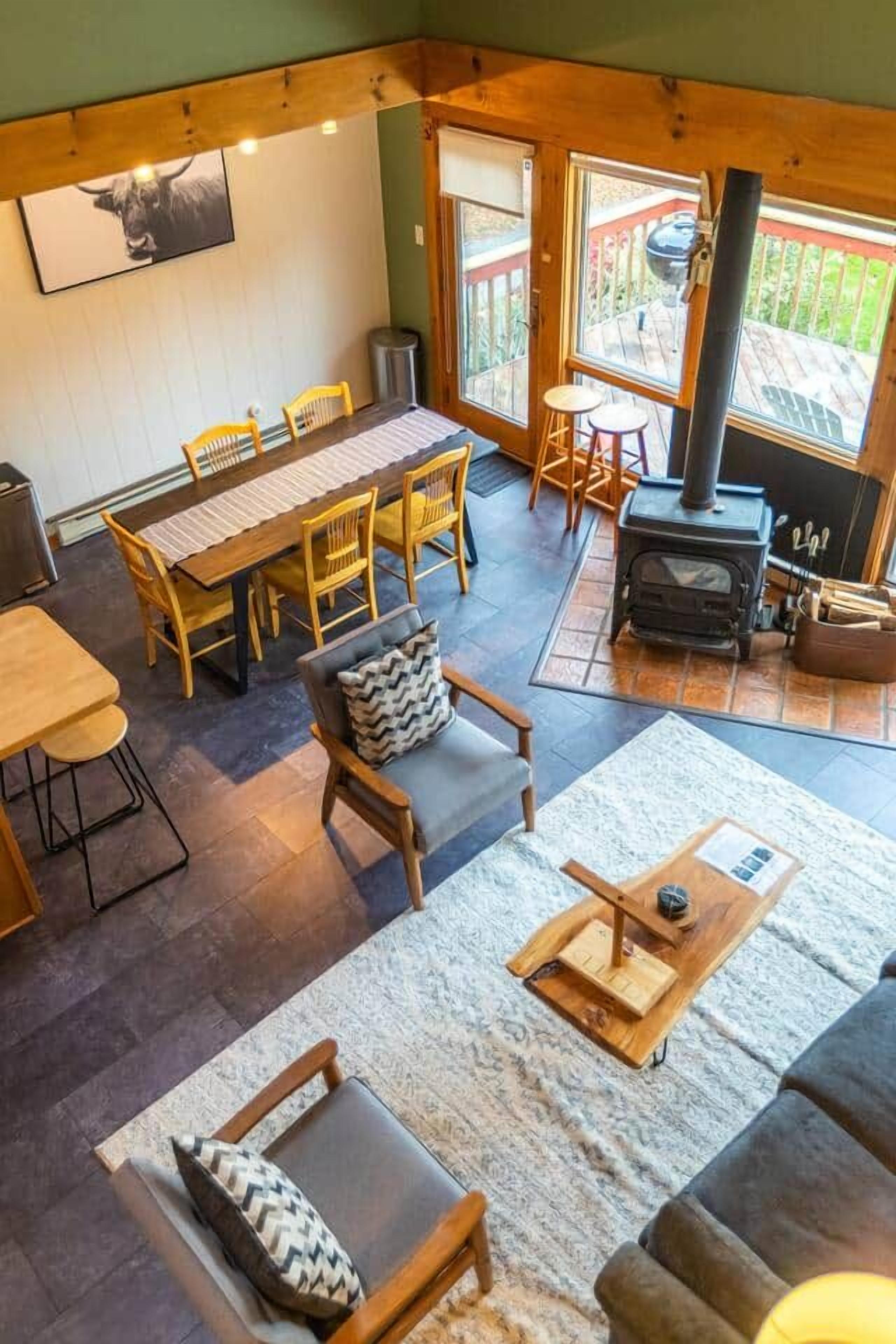 A cozy interior with a dining area, seating, and a wood-burning stove.