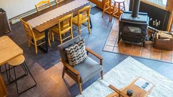 A cozy interior with a dining area, seating, and a wood-burning stove.