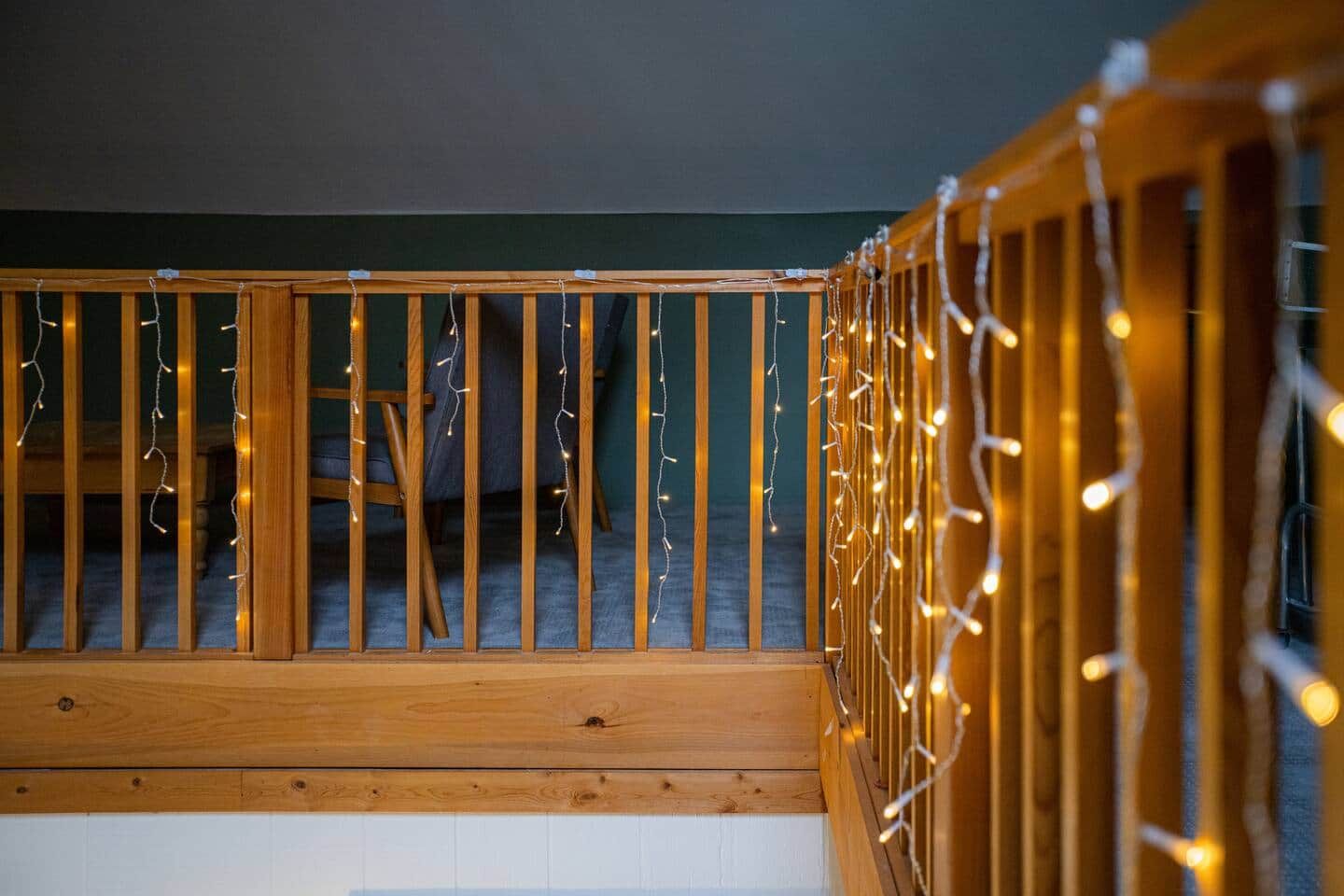 Une rambarde d’escalier en bois décorée de guirlandes lumineuses.