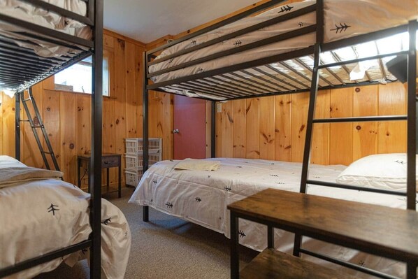 A bunk bed room with wooden walls, a red door, and a small table.