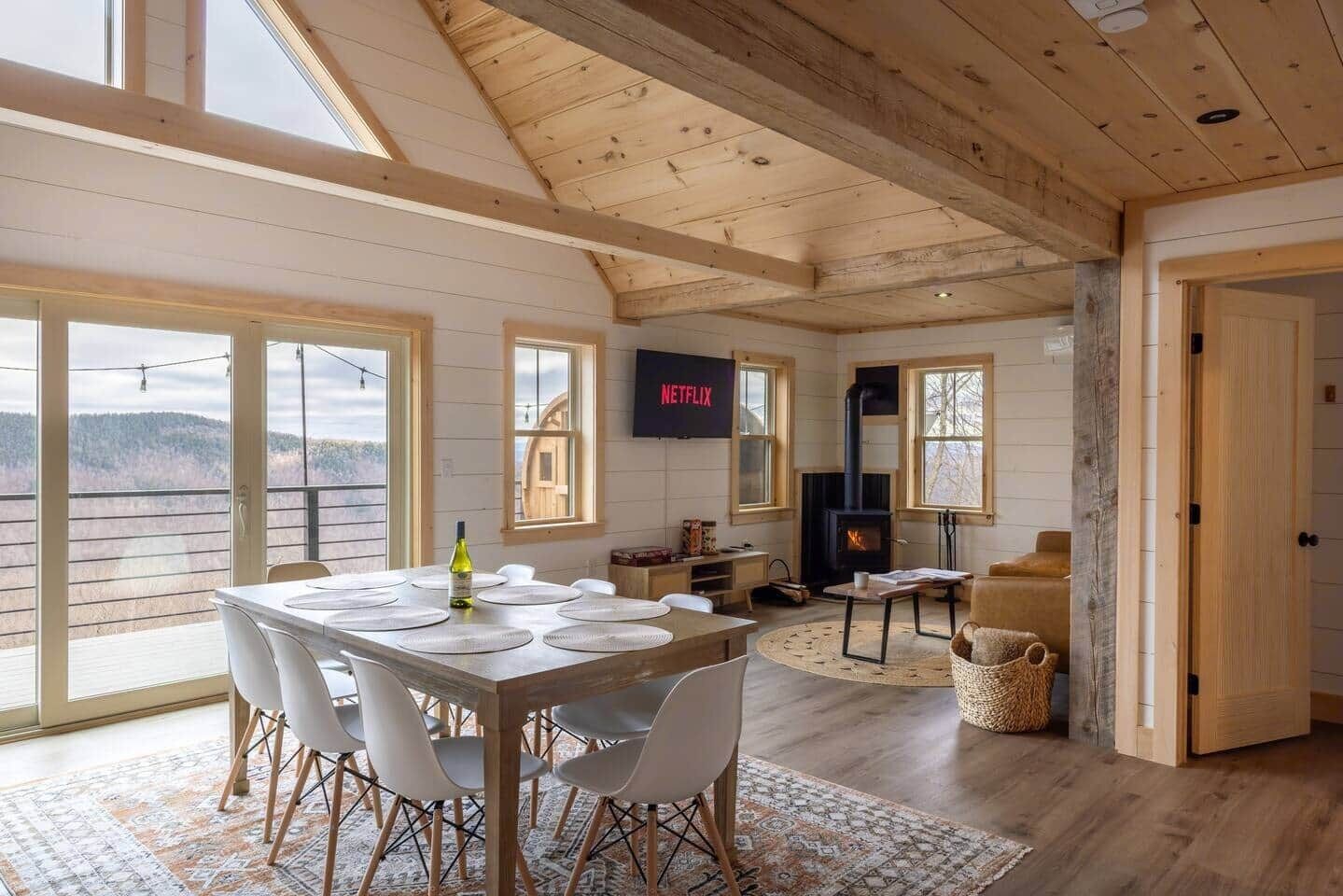 A spacious living area with a fireplace, a dining table with chairs, and a television mounted on the wall.
