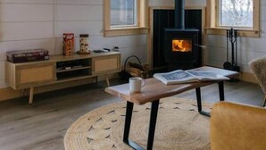 Ett mysigt vardagsrum med en öppen spis, en tv som är monterad på väggen och en bekväm sittgrupp.