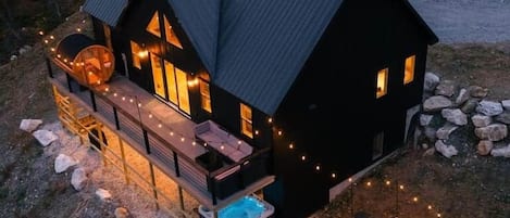 Una cabaña con terraza, jacuzzi y zona de fogata.