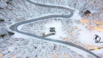 A winding road through a snowy landscape with a small building at the center.