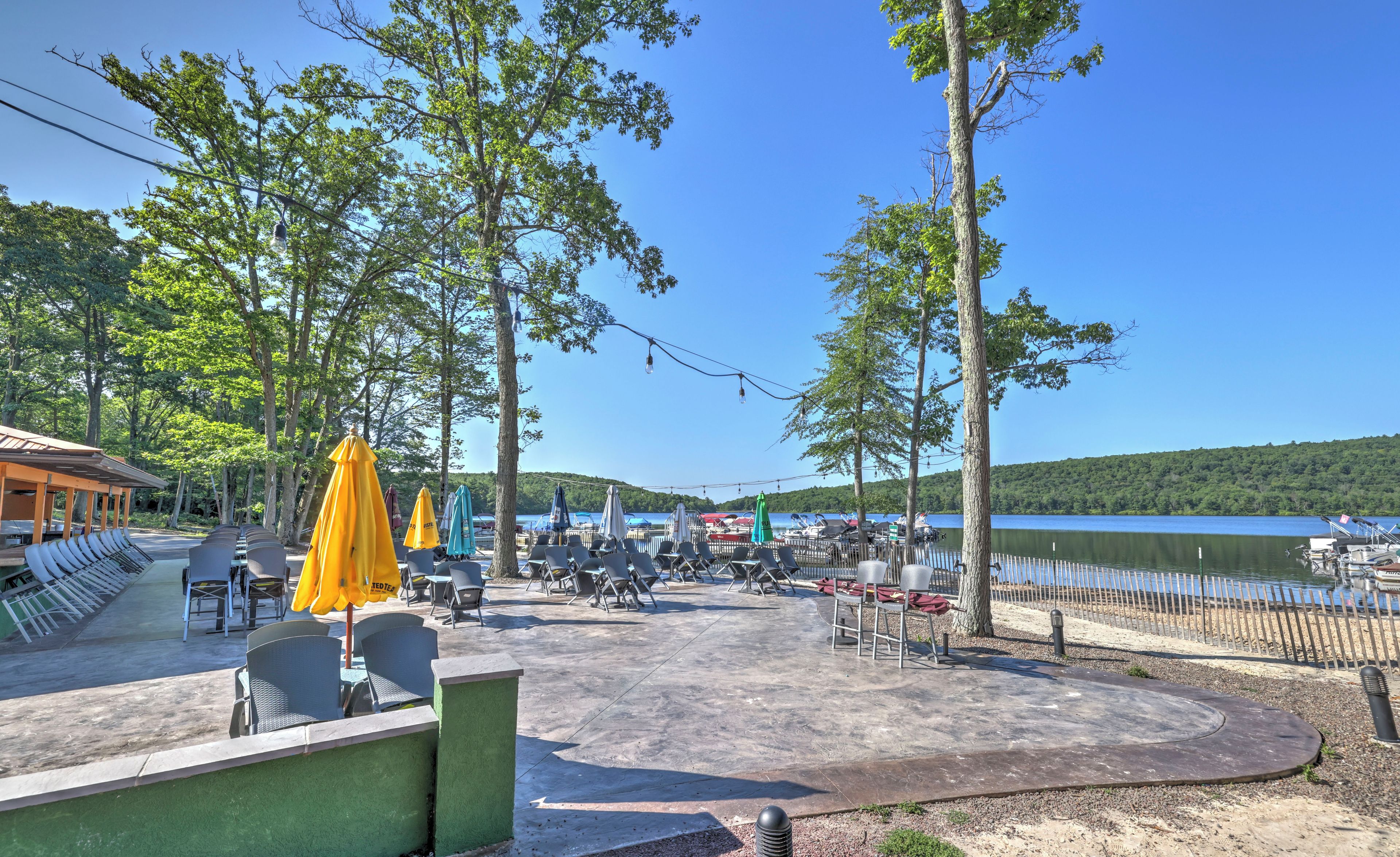 An outdoor seating area with chairs and umbrellas, overlooking a lake with boats and a dock.