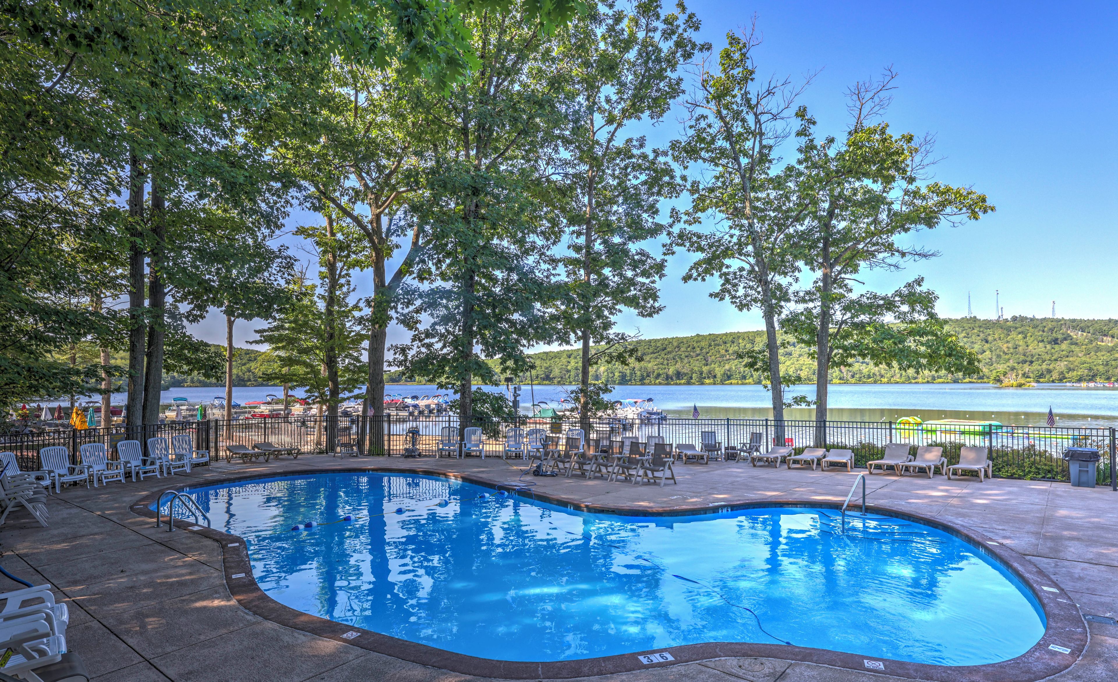 A swimming pool with lounge chairs and a view of a lake.