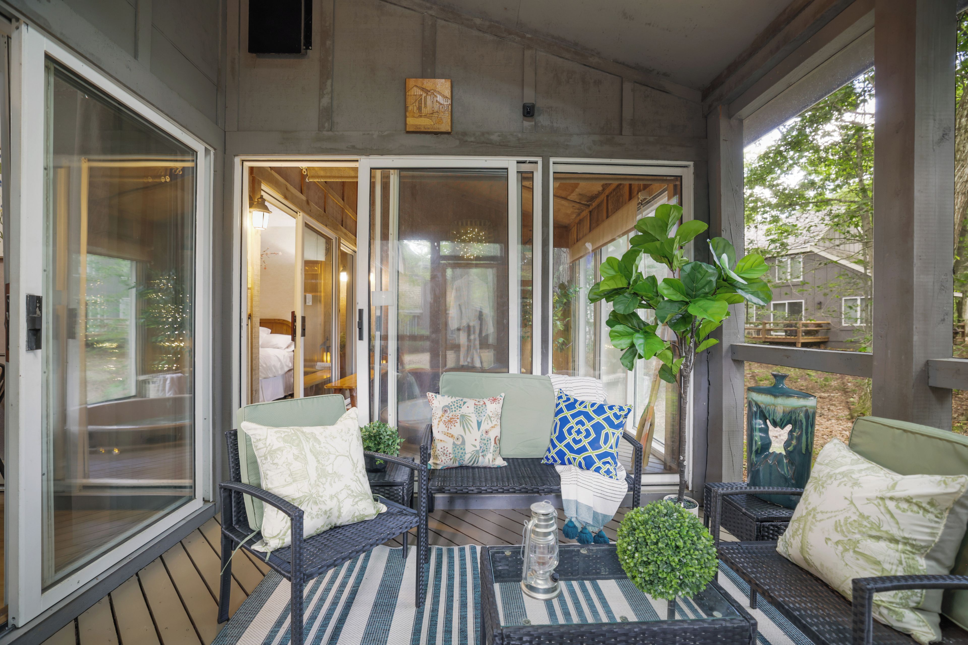 A covered patio with wicker furniture, a table, and a potted plant.