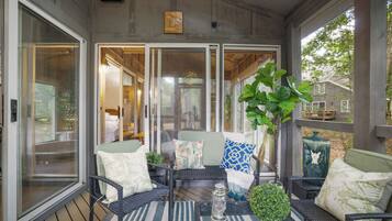 A covered patio with wicker furniture, a table, and a potted plant.