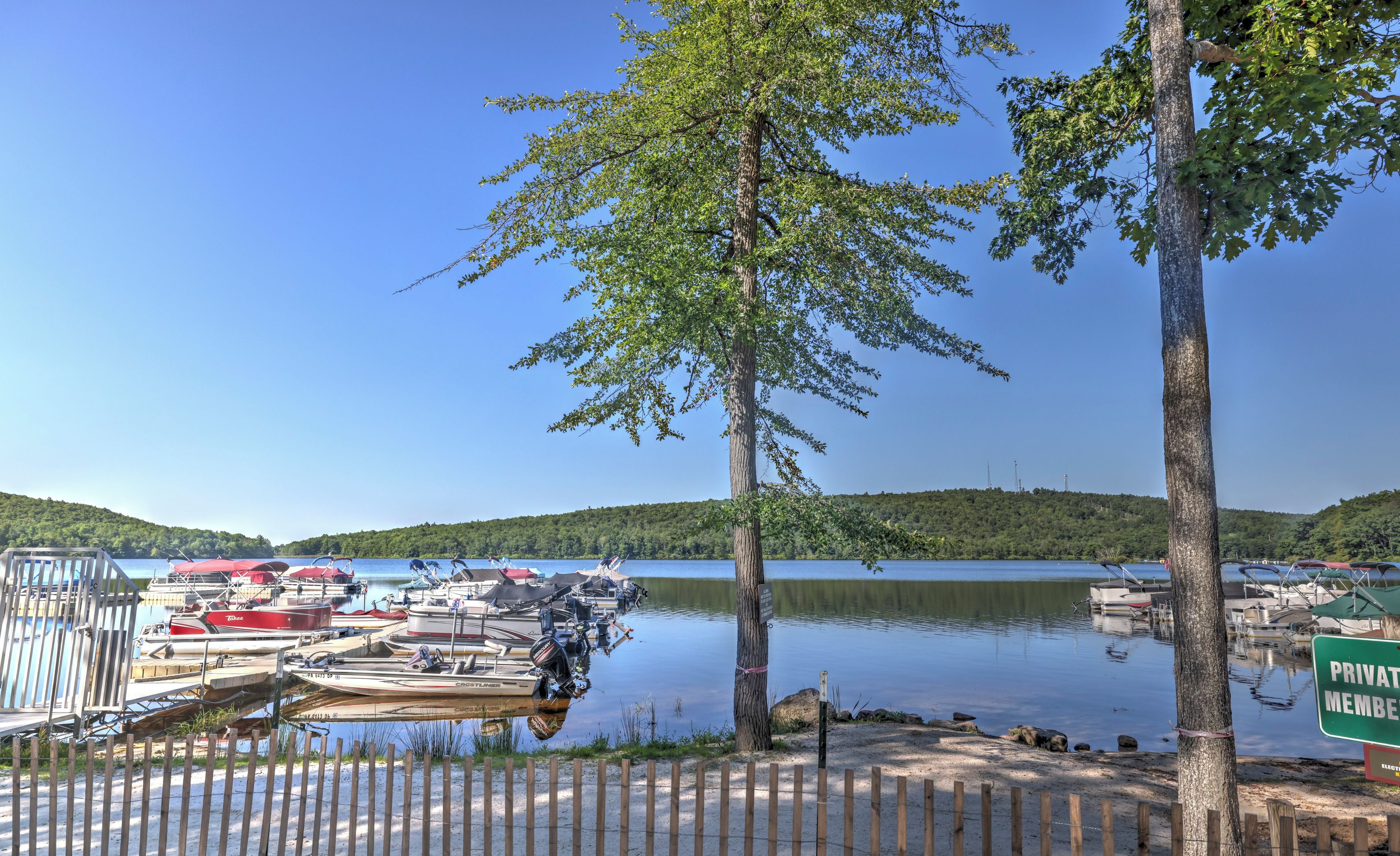 A marina with boats docked, a tree in the foreground, and a sign indicating private membership.