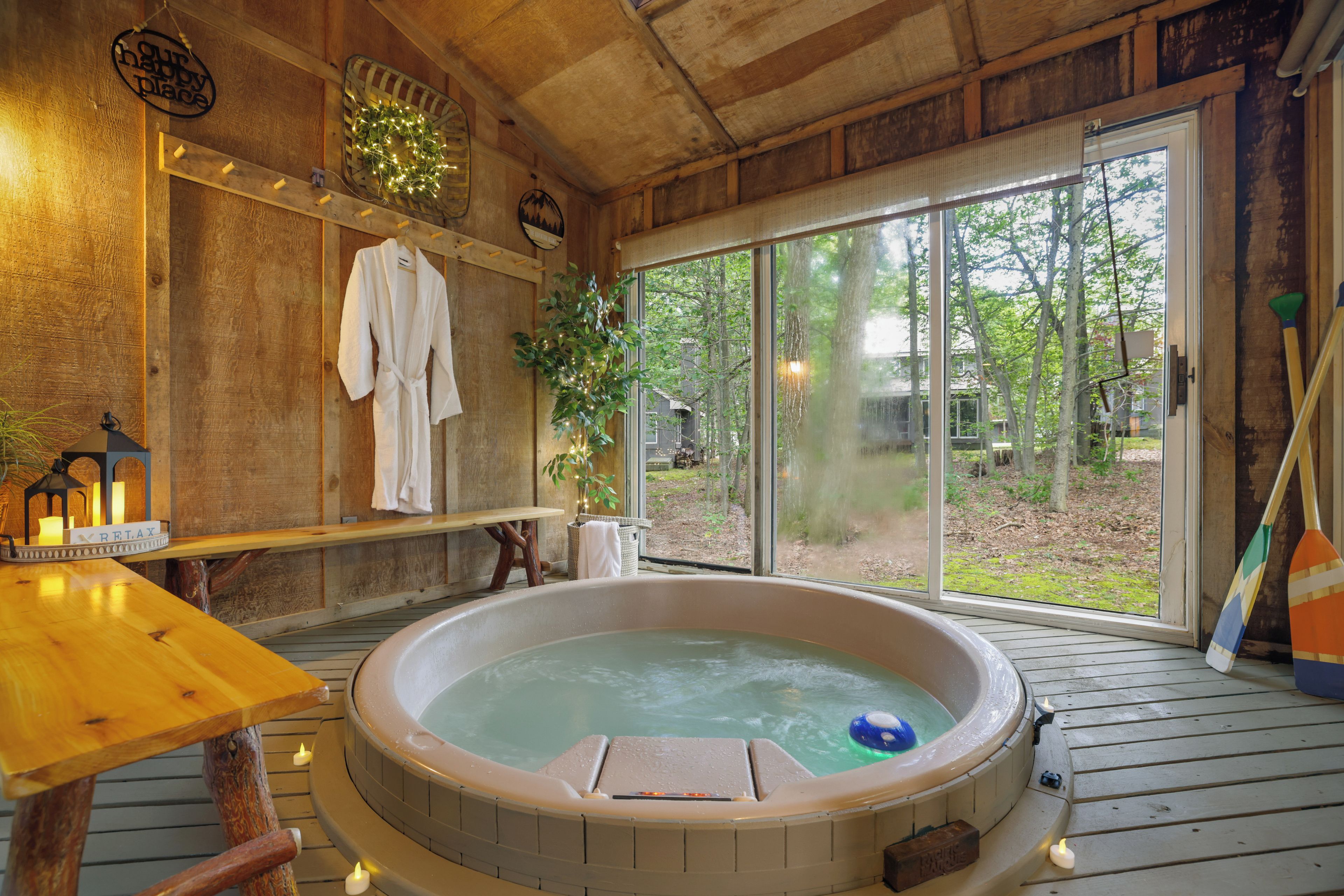 A hot tub in a wooden cabin with a view of the outdoors.