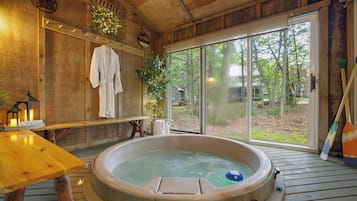 A hot tub in a wooden cabin with a view of the outdoors.