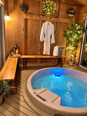 Ein hölzerner Wellnessbereich mit Whirlpool, einer Sitzbank und einem Bademantel an einem Kleiderständer.