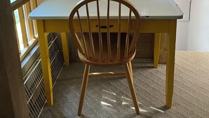 Een kleine eethoek met een houten stoel, een tafel en een hanglamp.
