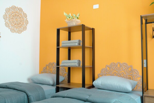 A room with a bed, a shelf with towels, and a decorative wall piece.