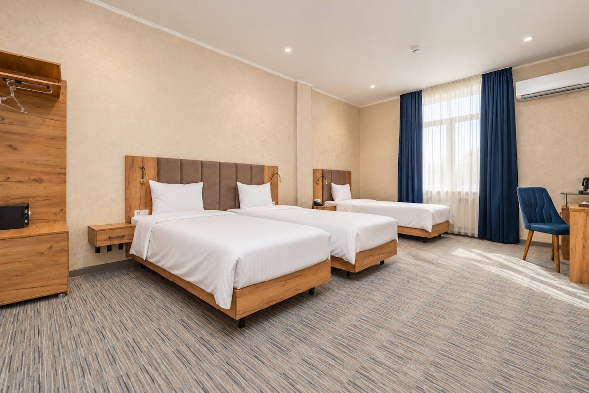 A hotel room with two beds, a desk, a chair, and a wardrobe.