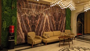A lobby with a marble wall, a sofa, a coffee table, and a patterned floor. - Hanzade Palace  (Samarkand)