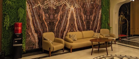 A lobby with a marble wall, a sofa, a coffee table, and a patterned floor.