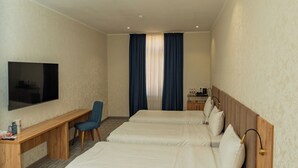 A hotel room with two beds, a desk, a chair, a TV, and a window with curtains. - Hanzade Palace  (Samarkand)