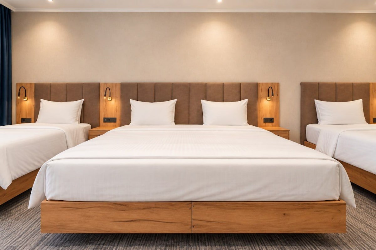 A hotel room with a large bed, two bedside tables, and wall-mounted lighting.