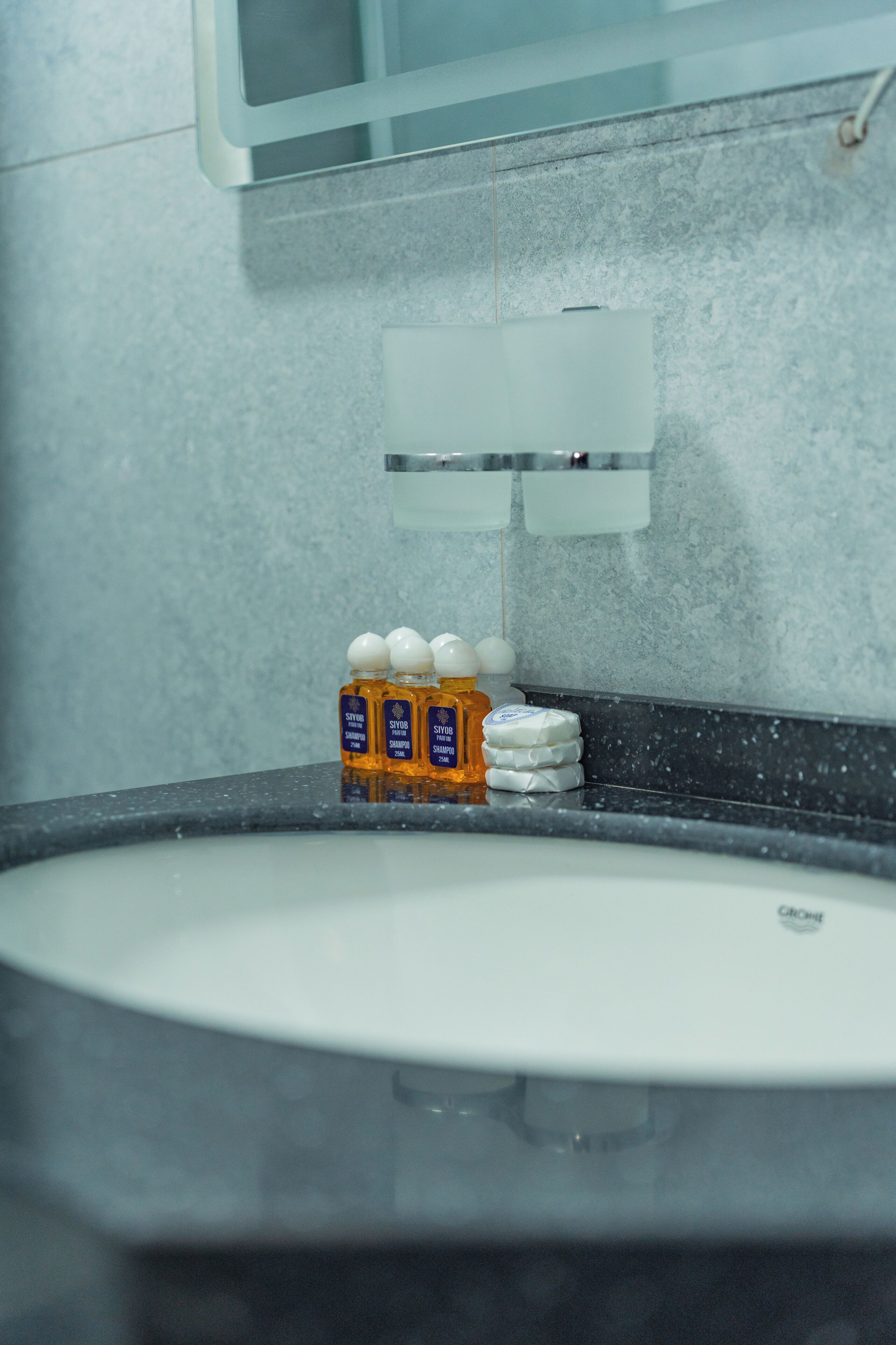 A bathroom with a sink, a mirror, and toiletries on the counter.