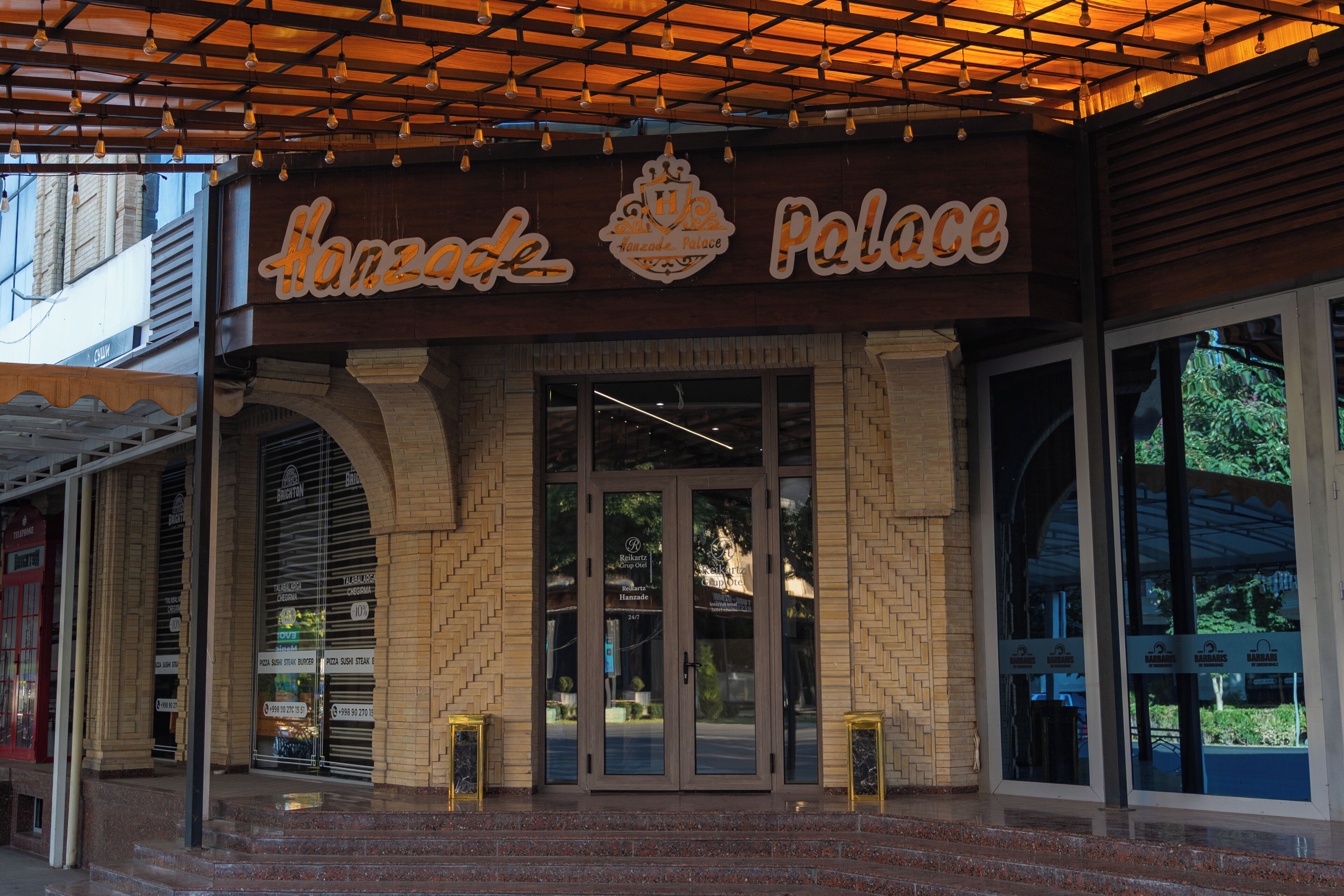 A building with a sign that reads 'Hanzade Palace' and a brick facade.