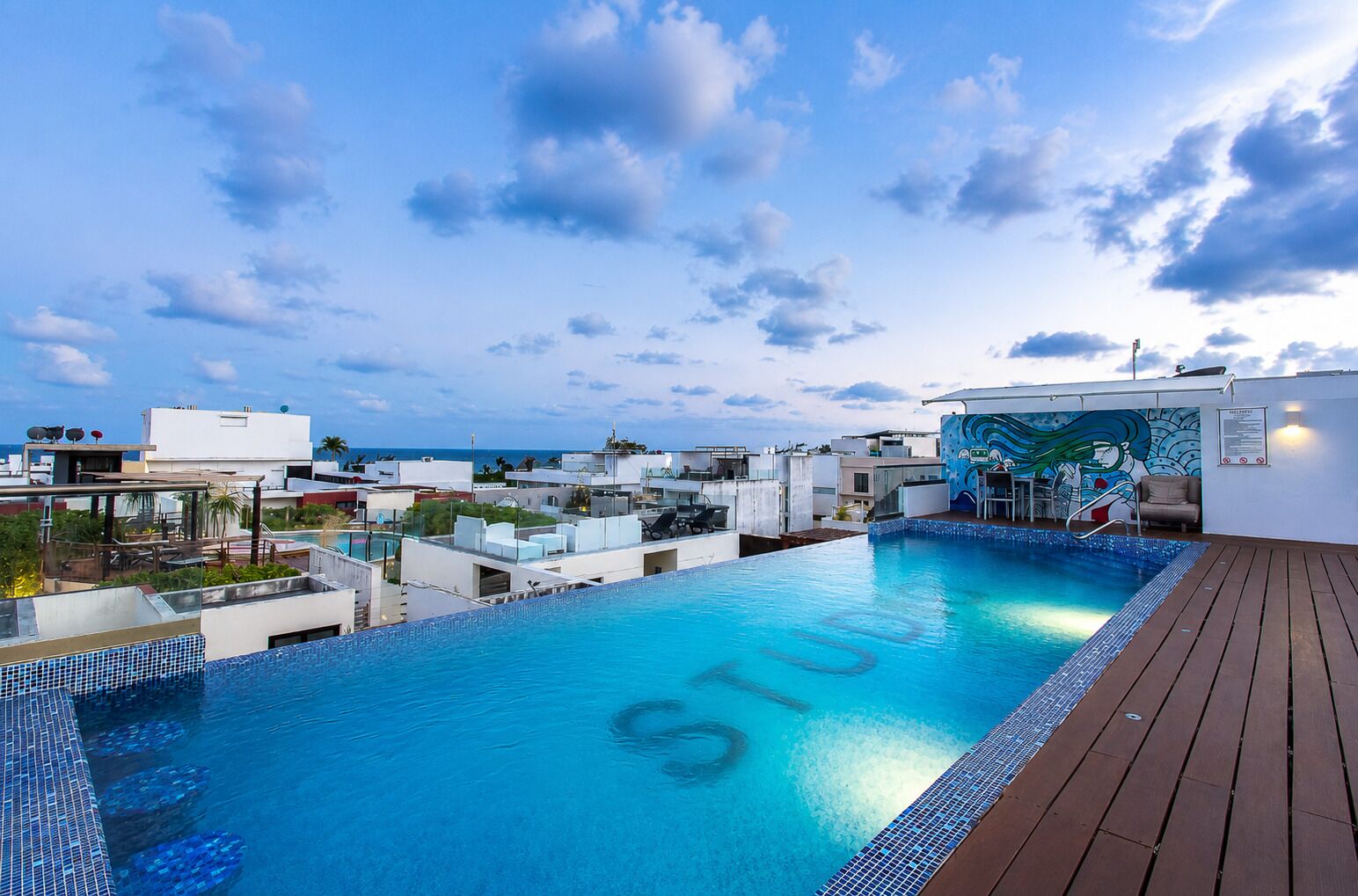 A rooftop swimming pool with a view of the cityscape and the sea.