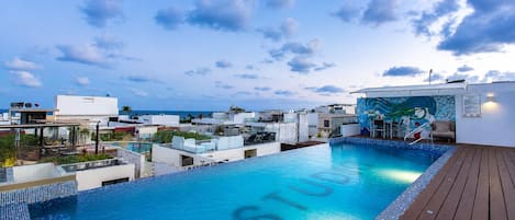 A rooftop swimming pool with a view of the cityscape and the sea.