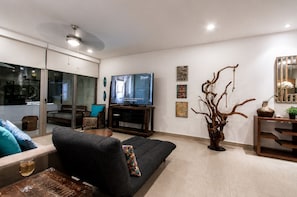 A modern living room with a sofa, a television, and a decorative tree sculpture. - Modern Apartment Pool & Balcony (Playa del Carmen)