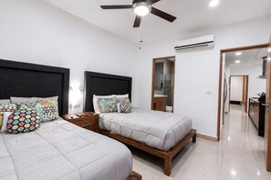 A bedroom with two beds, a ceiling fan, an air conditioning unit, and a mirror. - Modern Apartment Pool & Balcony (Playa del Carmen)