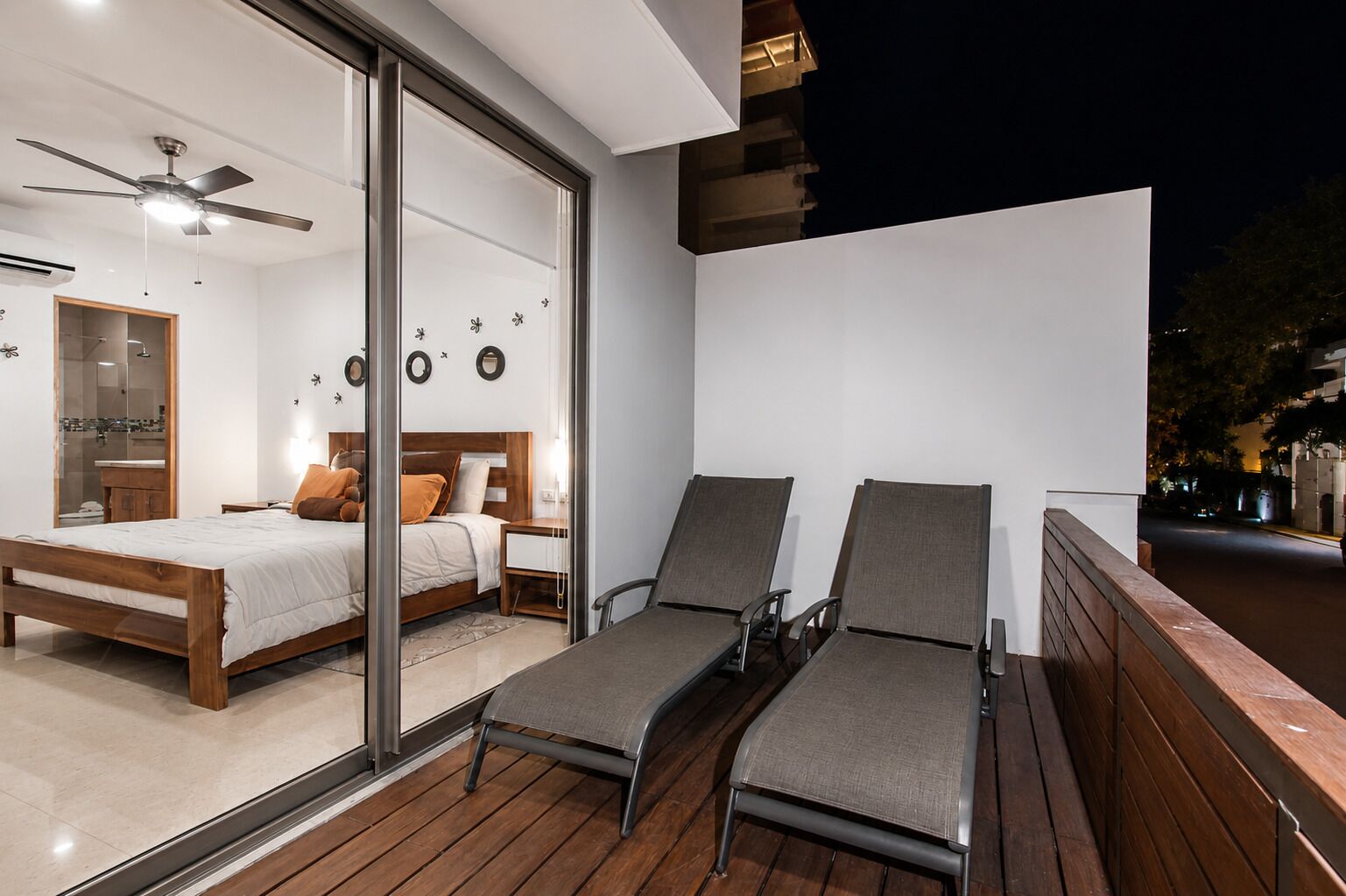A balcony with two lounge chairs and a wooden deck.