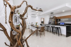 A modern kitchen with a central island, bar stools, and a dining area with chairs and a table. - Modern Apartment Pool & Balcony (Playa del Carmen)