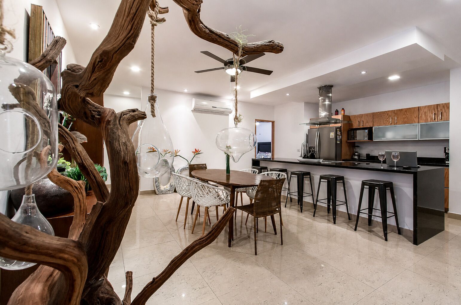 Una cocina moderna con comedor, que incluye una isla central, taburetes de bar y un ventilador de techo.