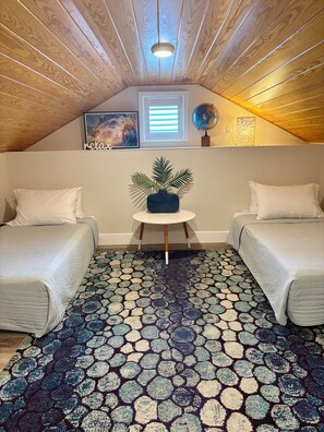 A bedroom with two beds, a small round table, a globe, and a framed picture on the wall. - Gorgeous Hideaway w/pool in Historic Downtown NSB (New Smyrna Beach)
