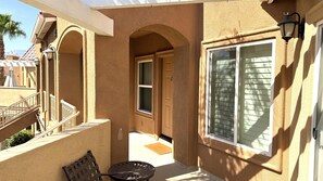 A covered outdoor area with a bench, a door, and a window with shutters. - Walking distance from the World Famous, Indian Wells Tennis Gardens (La Quinta)