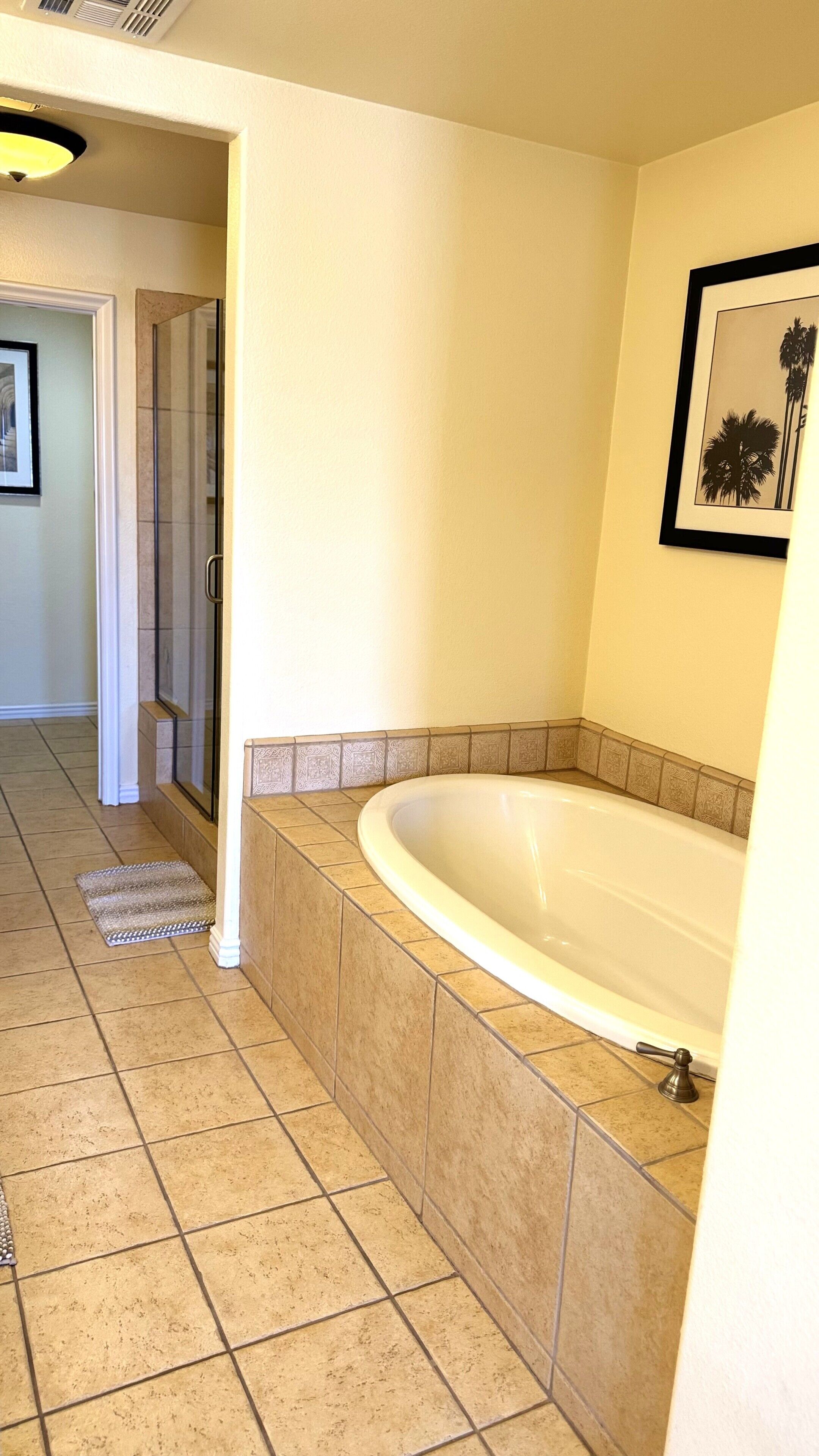 Un baño con una bañera grande, suelo de baldosas y un cuadro en la pared.