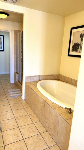 A bathroom with a large bathtub, tiled floor, and a framed picture on the wall. - Walking distance from the World Famous, Indian Wells Tennis Gardens (La Quinta)