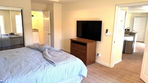 A hotel room with a bed, a TV, a dresser, and a bathroom visible through an open door. - Walking distance from the World Famous, Indian Wells Tennis Gardens (La Quinta)
